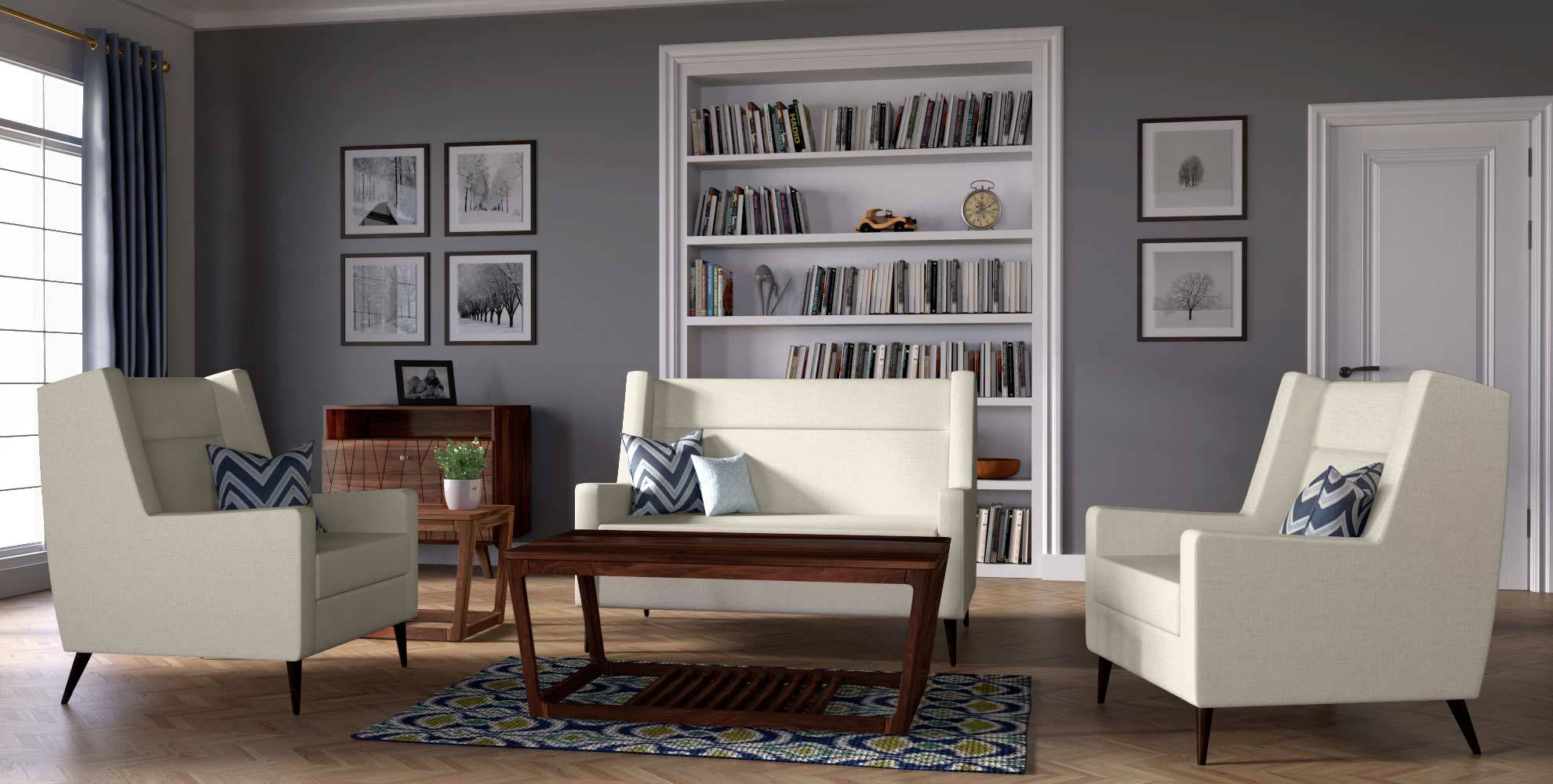 Living room with cream armchairs and sofa, wooden coffee table, patterned rug, bookshelf, and framed prints