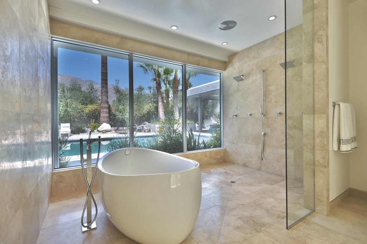 Spacious bathroom with a freestanding oval white tub, glass shower, and beige tile walls